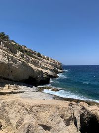 Rock formation on beach against clear blue sky