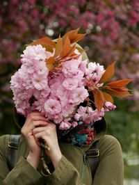 Close-up of woman holding pink flowers over face