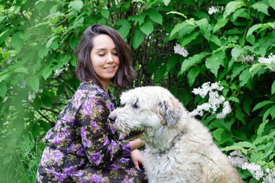 Smiling young woman with dog by plants