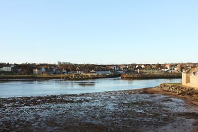 Bridge over river in city against clear sky