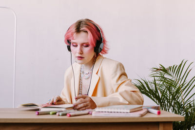 Creative young woman using smartphone , listen to music at table with scetchbook and markers