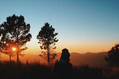 Silhouette woman standing on field against clear sky during sunset