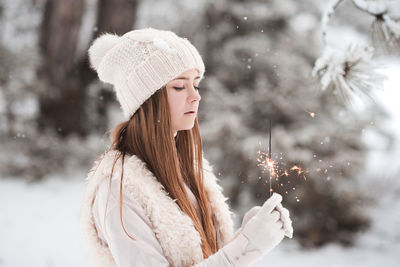 Teenager girl holding sparkler during winter