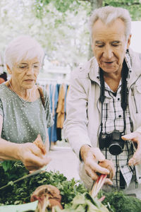 Senior man and woman shopping for vegetables at street market in city