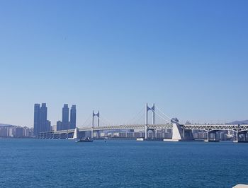 Suspension bridge over river against clear blue sky