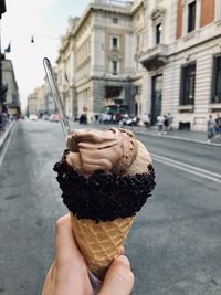 Cropped hand of woman holding ice cream cone on street