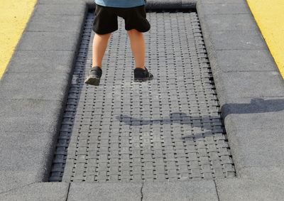 Low section of boy jumping on trampoline