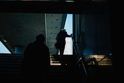 Rear view of silhouette man standing by window
