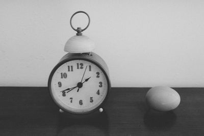 Clock on table against white wall