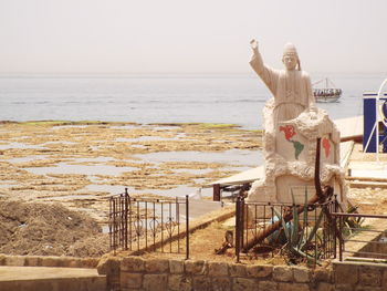 Sculpture by sea against clear sky