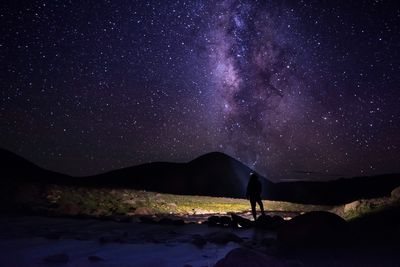 Silhouette woman standing on mountain against star field