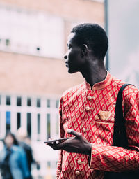 Man holding red while standing against blurred background