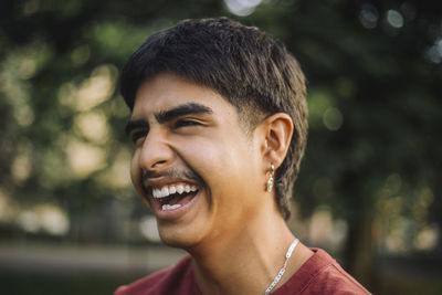 Happy teenage boy laughing at park