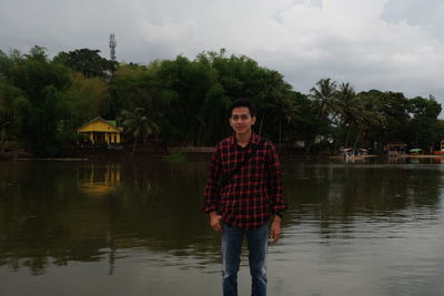 Portrait of man standing in lake against sky