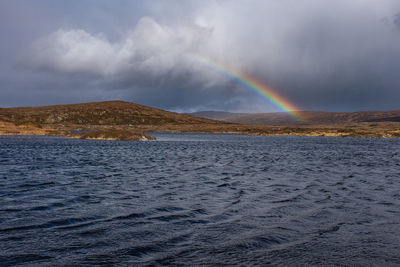 Scenic view of rainbow over sea against sky