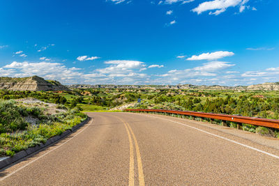 Road leading towards landscape against sky