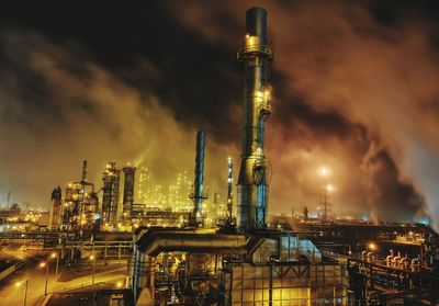 Illuminated factory against sky at night