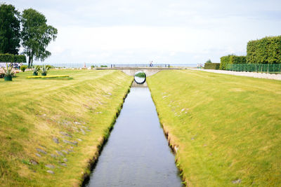Scenic view of canal amidst field against sky
