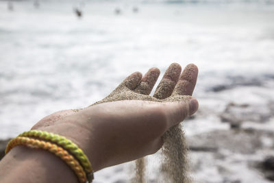 Close-up of hand holding sand at beach