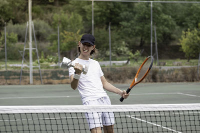 Young man tennis player celebrating his victory of the competition with a cup in his hand