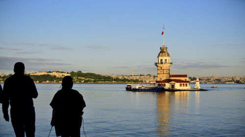 Rear view of people while viewing kizkulesi in uskudar by sea against sky