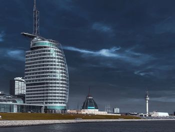 Modern buildings in city against cloudy sky