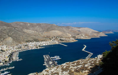 High angle view of sea by mountains against blue sky