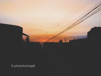 Silhouette telephone pole against sky during sunset