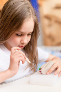 Felt wool craft by handmade needle. kid girl artisan hand makes a creative toy made of sheep hair