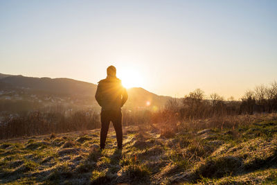 Wide angle of a man from behind facing a view of landscape consists of mountain during sunrise rays
