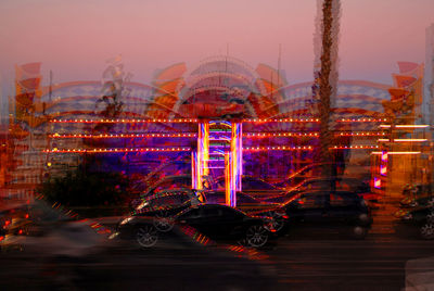 Blurred image of car and illuminated amusement park