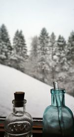 Bottles on window against snow covered field