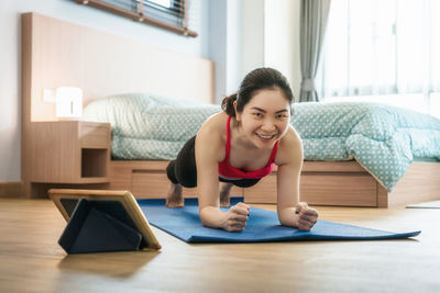 Smiling young woman using mobile phone at home