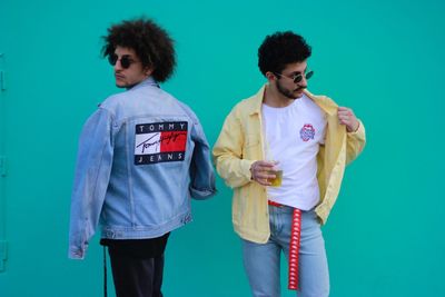 Fashionable young men standing against green background