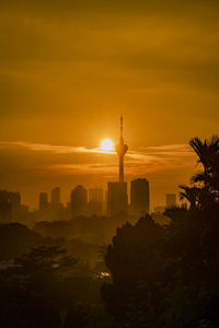 Silhouette of buildings against cloudy sky during sunset