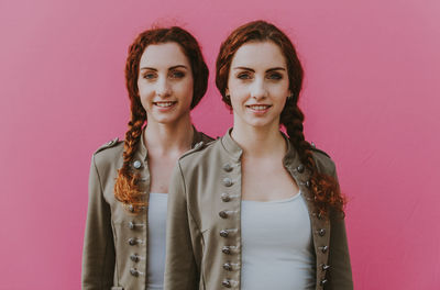 Portrait of a smiling young woman against pink background