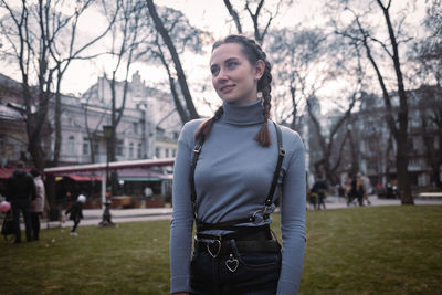 Portrait of young woman standing against trees