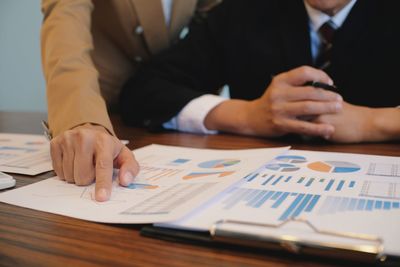 Midsection of businessmen working on graph at desk