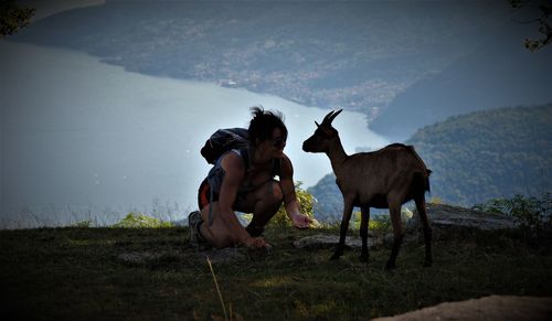 Female hiker with goat on mountain against sea