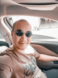 Portrait of man wearing sunglasses sitting in car