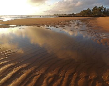 Surface level of sandy beach against sky during sunset