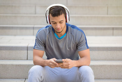 Young man using mobile phone while sitting on staircase