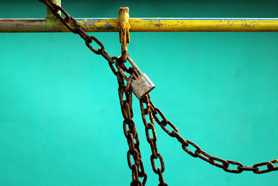 Low angle view of chain on fence against blue sky
