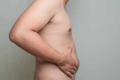 Midsection of shirtless man with woman standing against white background