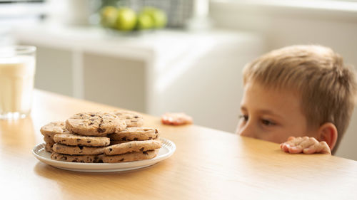Close-up of cute boy with cookies on table