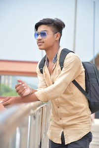 Young man wearing sunglasses standing by railing