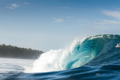 Waves splashing on sea against sky