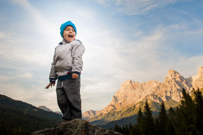 Low angle view of woman standing on mountain against sky