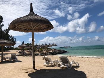 Deck chairs on beach against sky