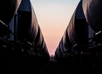 Silhouette freight trains against sky during sunset